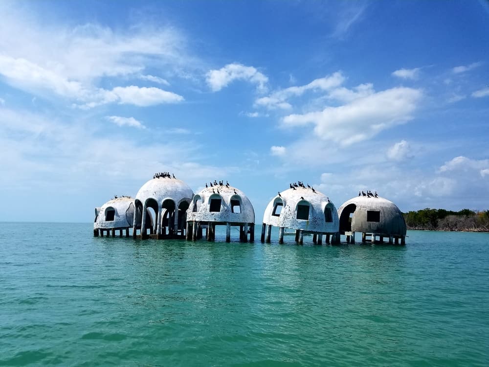The dome houses are abandoned and on stilts, surrounded by water. 