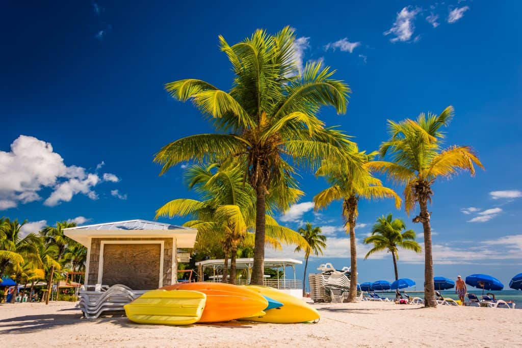 Beach with kayaks, beach chairs, and palm trees in Key West, Florida.