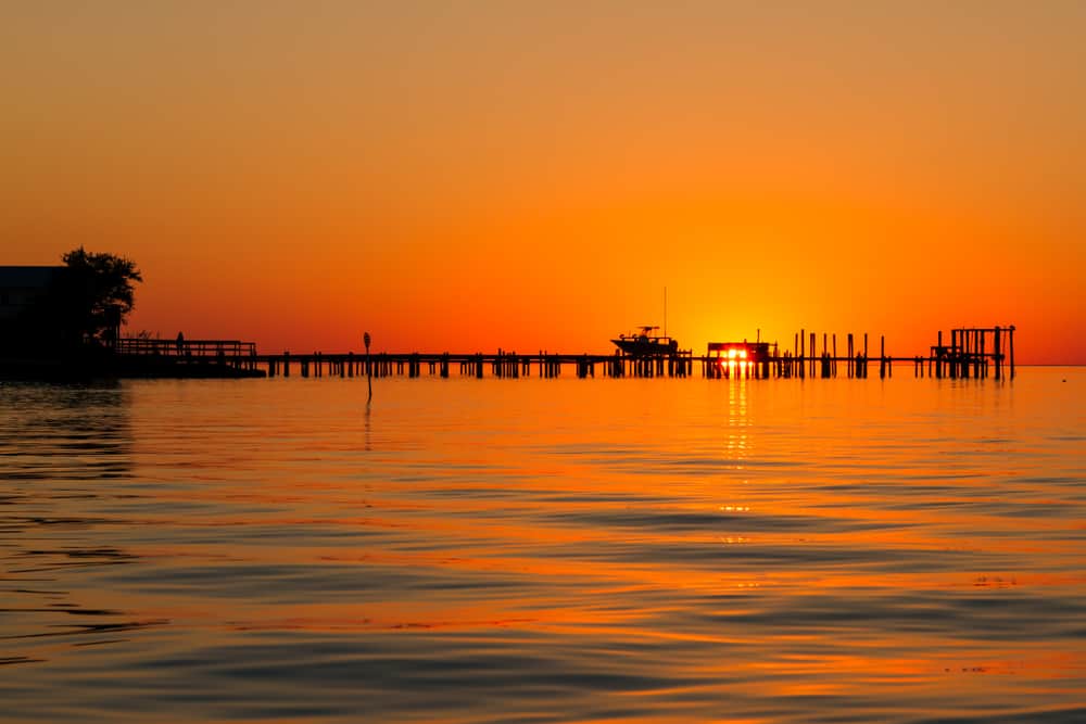 bright orange sunrise behind pier