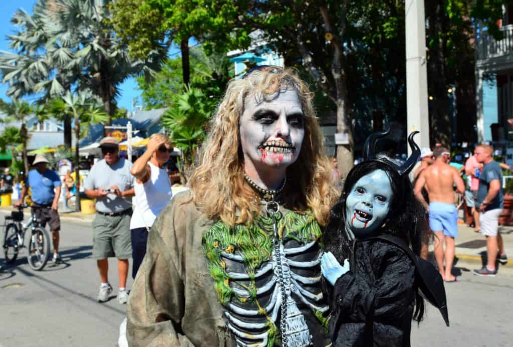 A cosplayer with ghoulish makeup holds a prosthetic demon baby at Fantasy Fest in Key West.