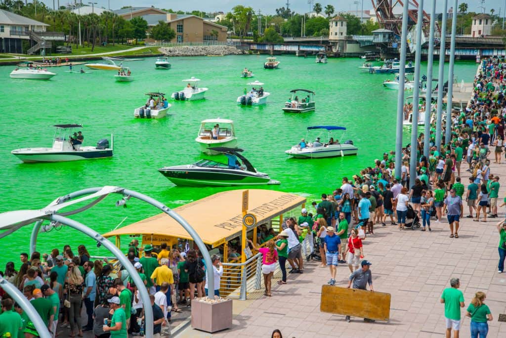 Boats sail along the Hillsborough River, dyed green for the River O'Green Festival in Tampa, Florida.
