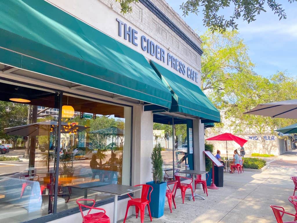 The Cider Press Café exterior with tables, chairs, and umbrellas, one of the best vegan restaurants in St. Petersburg Florida.