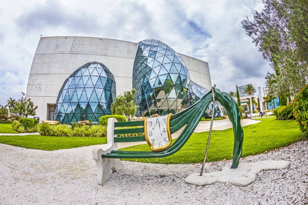 A twisted bench sculpture in front of the glass domes of the Salvador Dali Museum, one of the best things to do in St. Petersburg, FL.