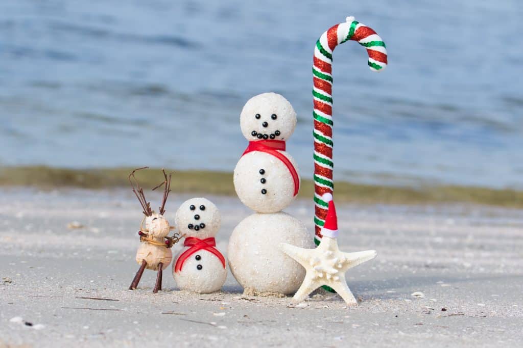 Snowmen made of sand celebrate winter in Florida on a beach!