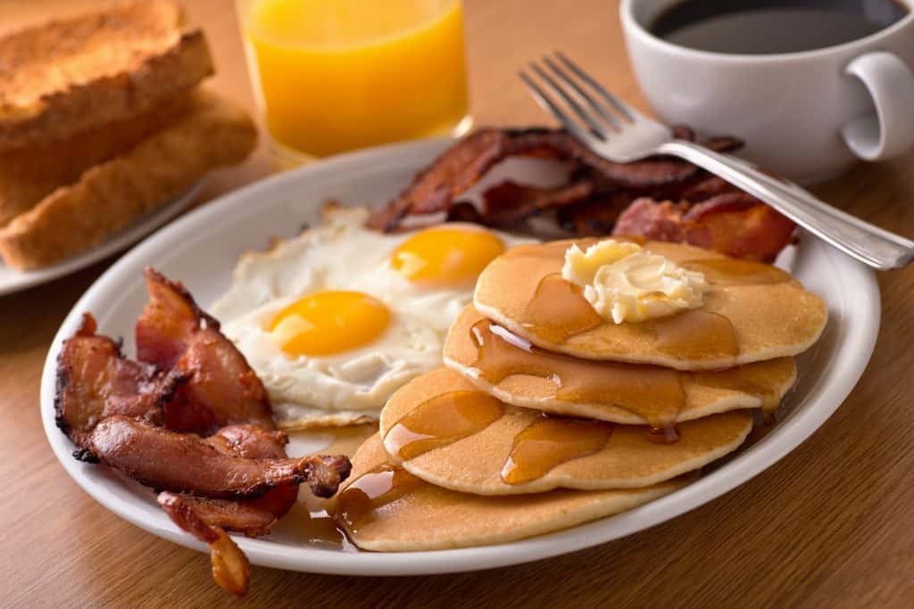 A breakfast platter holds bacon, eggs, and pancakes.