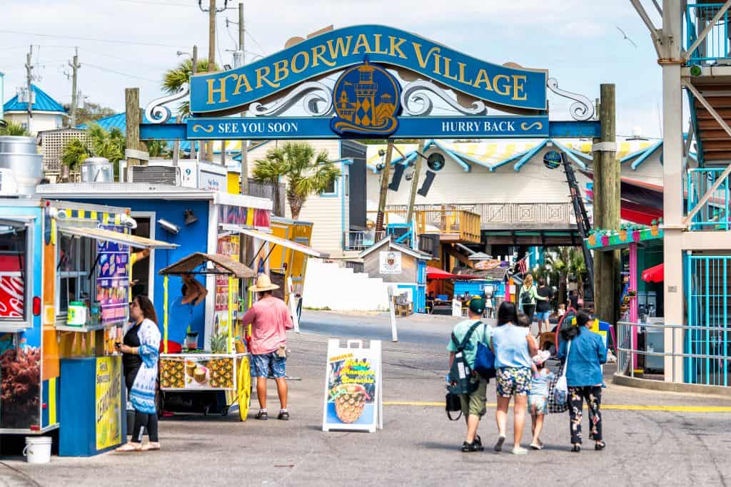 People walking around the entrance to Harborwalk Village on the Destin Harbor Boardwalk, one of the best things to do in Destin.