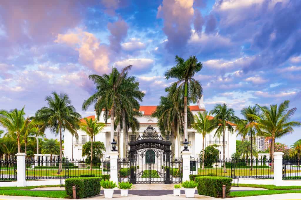 The ornate and beautifully decorated Flagler Museum surrounded by palm trees at sunset.