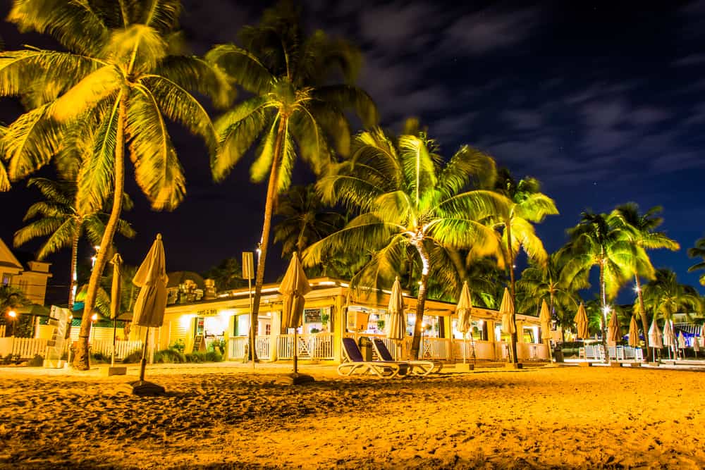 A restaurant lit up at night, surrounded by palm trees, at South Beach in Key West, one of the low-key beaches in Key West.