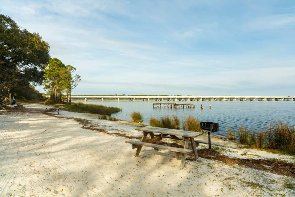 A picnic table and grill sit on the coastal dunes of Camp Helen State Park, one of the best things to do in Panama City Florida.