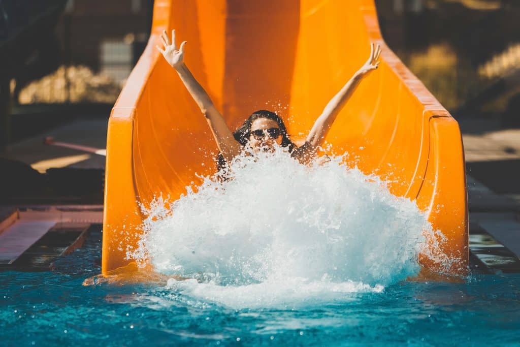 A young girl splashes down at the end of a bright orange waterslide at Shipwreck Island in Panama City, Florida.