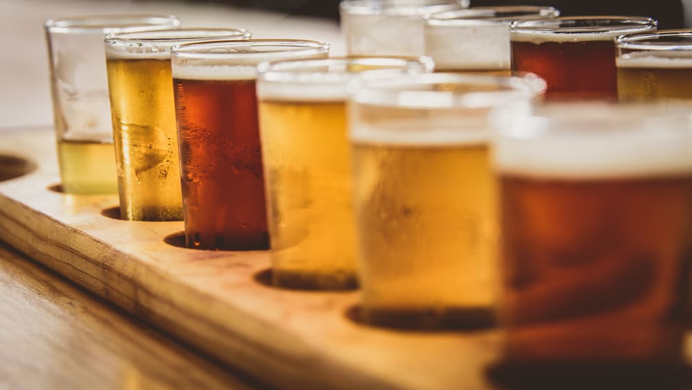 A beer flight sits on a bar, each selection a slightly different shade of amber.