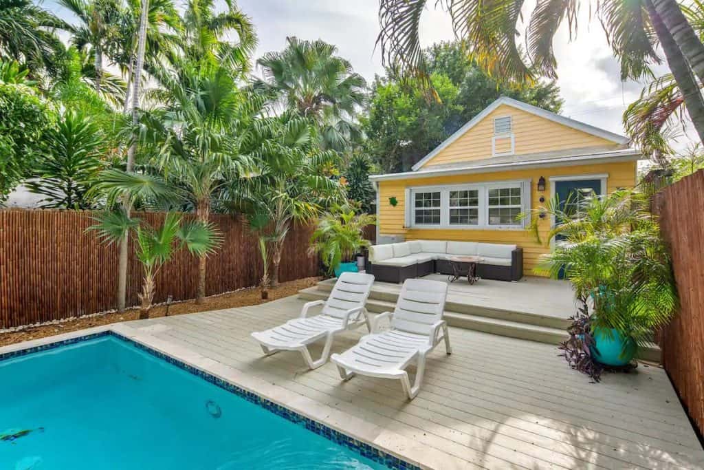 Photo of a yellow home with a back pool deck and seating area. 