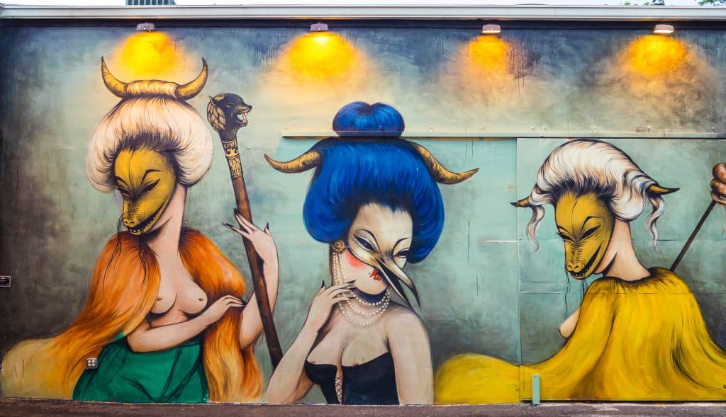 A mural at the Wynwood Walls depicts three women wearing masks representing various animals.