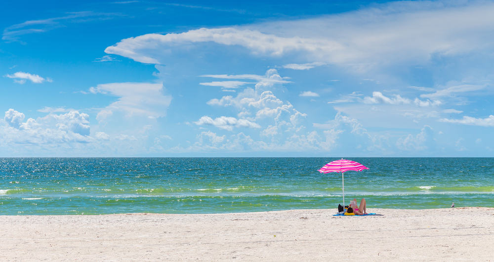 A couple under an umbrella on St Pete's beach. One of the best florida beaches for couples 