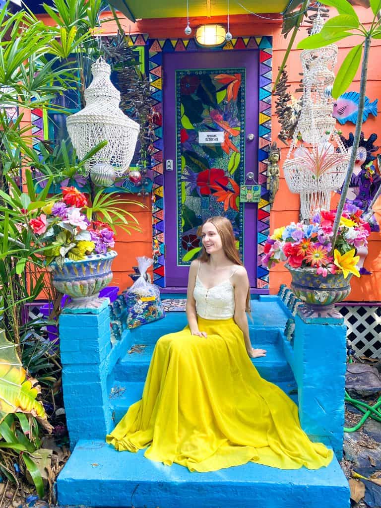 Victoria sits in a vibrant yellow skirt on the blindingly colorful decorations of Whimseyland in Safety Harbor.
