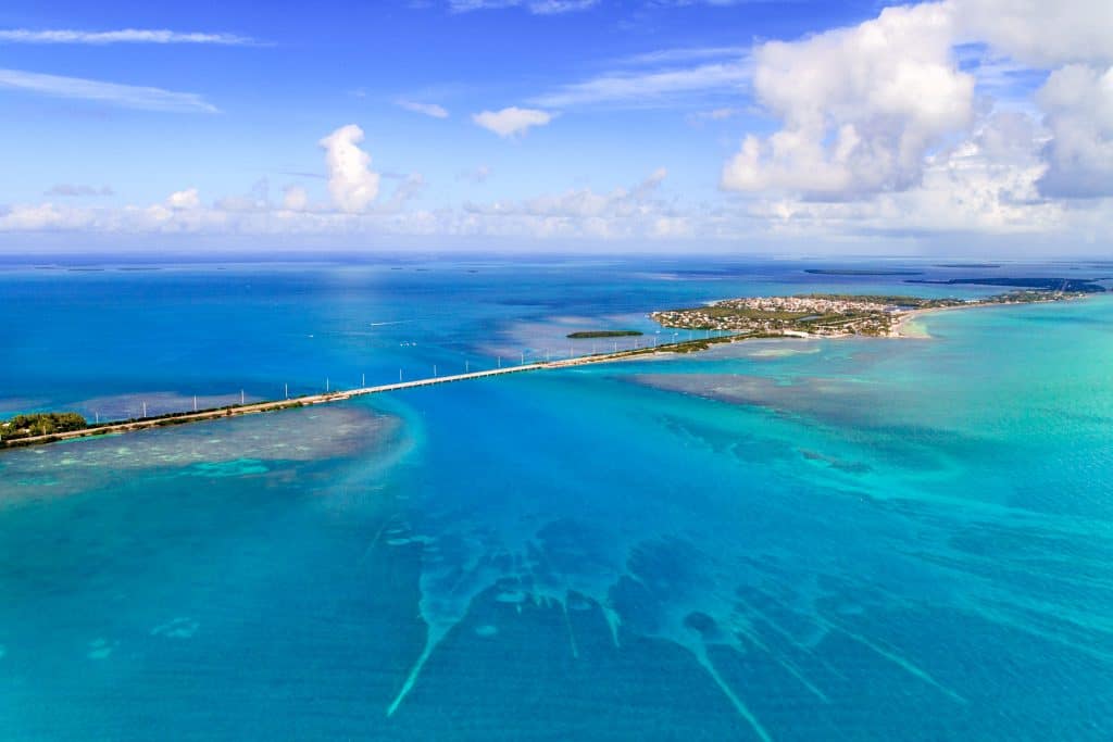 An aerial shot of the Seven Mile Bridge connects the Florida Keys together, surrounded by piercingly blue ocean waters.