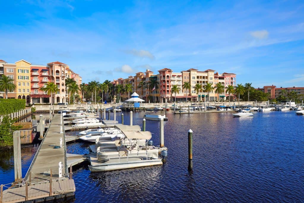 The Naples bay marina shimmers with its colorful buildings in the background.