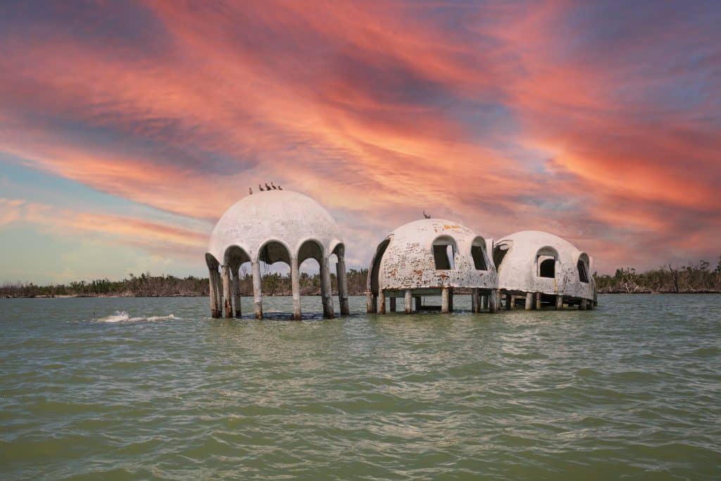 The Florida Domes float above the water while the sunset casts a pink glow on the clouds overhead. 