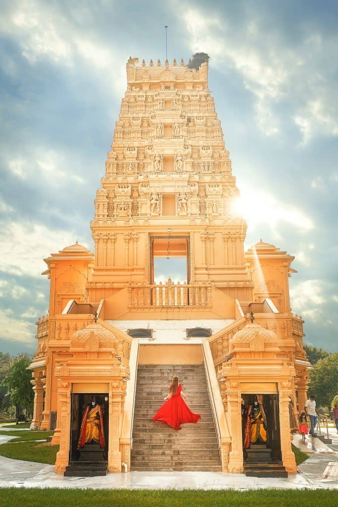 Girl in red dress posses on the steps of the religious Hindu Temple in Florida
