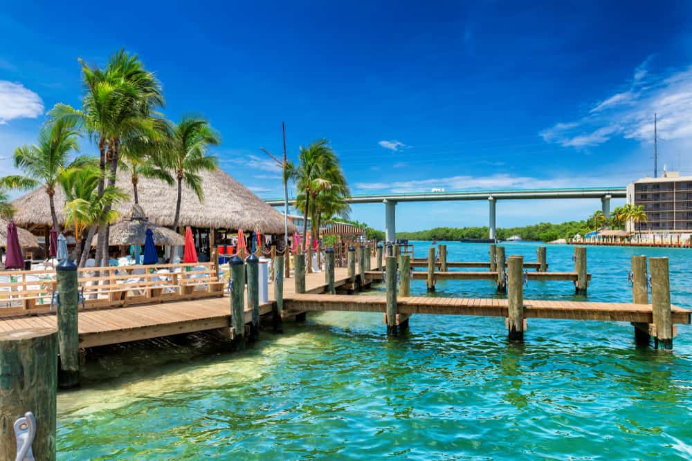 Beautiful Turquoise water in Key largo with a dock, tiki hut and bridge in background
