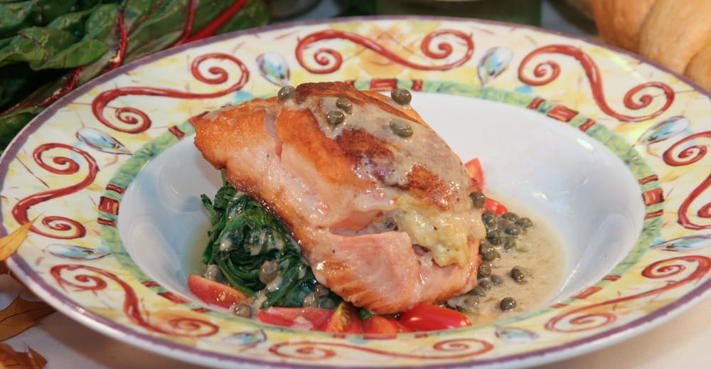 Fish with lemon caper sauce , sautéed spinach and tomatoes on a colorful plate