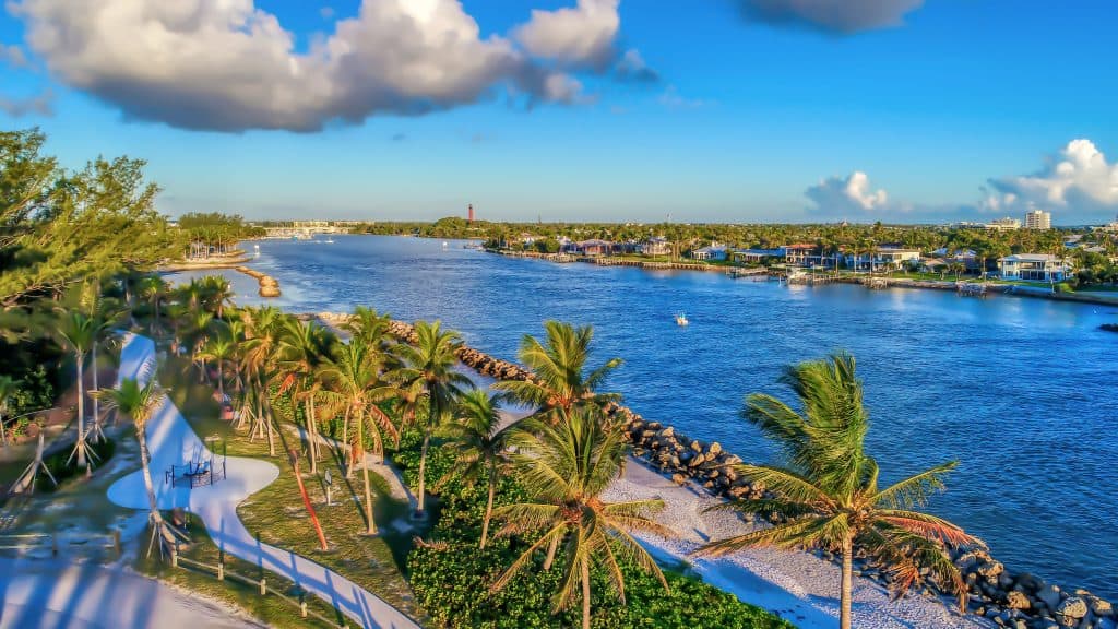 The beautiful blue waters, paved trails, and swaying palm trees of Dubois Park, one of the best things to do in Jupiter.