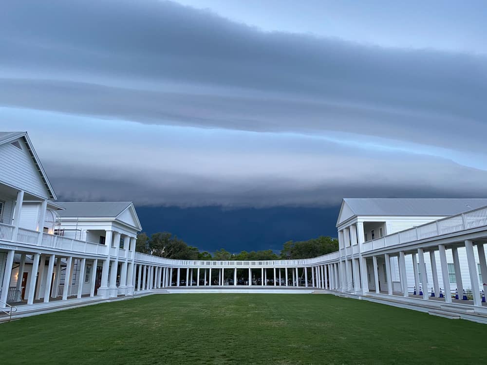 The grassy lawn in front of the amphitheater, surrounded by a columned walkway and buildings in Seaside, Florida.
