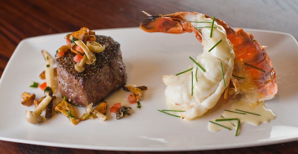 A surf and turf, the steak is topped with mushrooms and the lobster tail in a butter sauce 