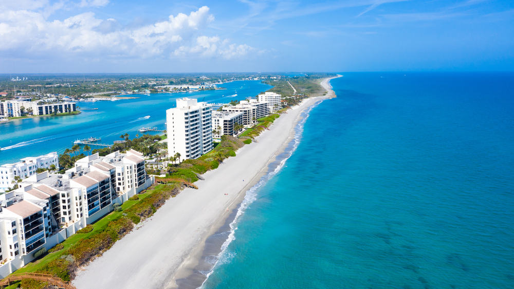 The beautiful blue water of Jupiter Island with buildings and white sand