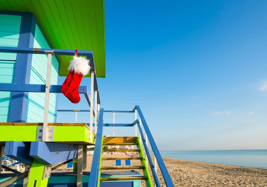 lifeguard stand in Miami with a Christmas Stocking hanging on it with blue water showing christmas in florida