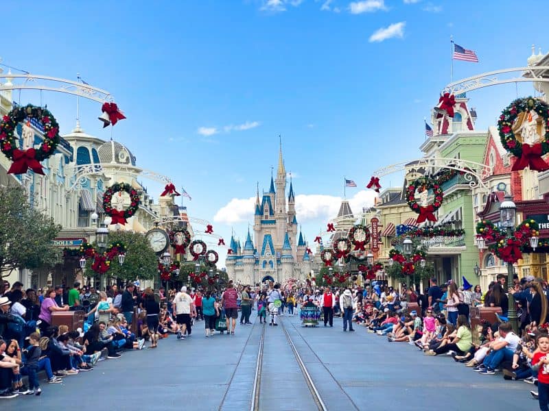 Main street at disney world lined with wreaths and people for a Florida Christmas parade