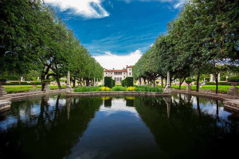 View of Vizcaya across a pond and surrounded by trees.