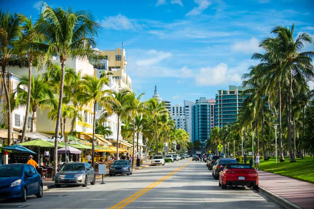 Photo of busy beach street in Miami with lots of colorful cafe umbrellas. 