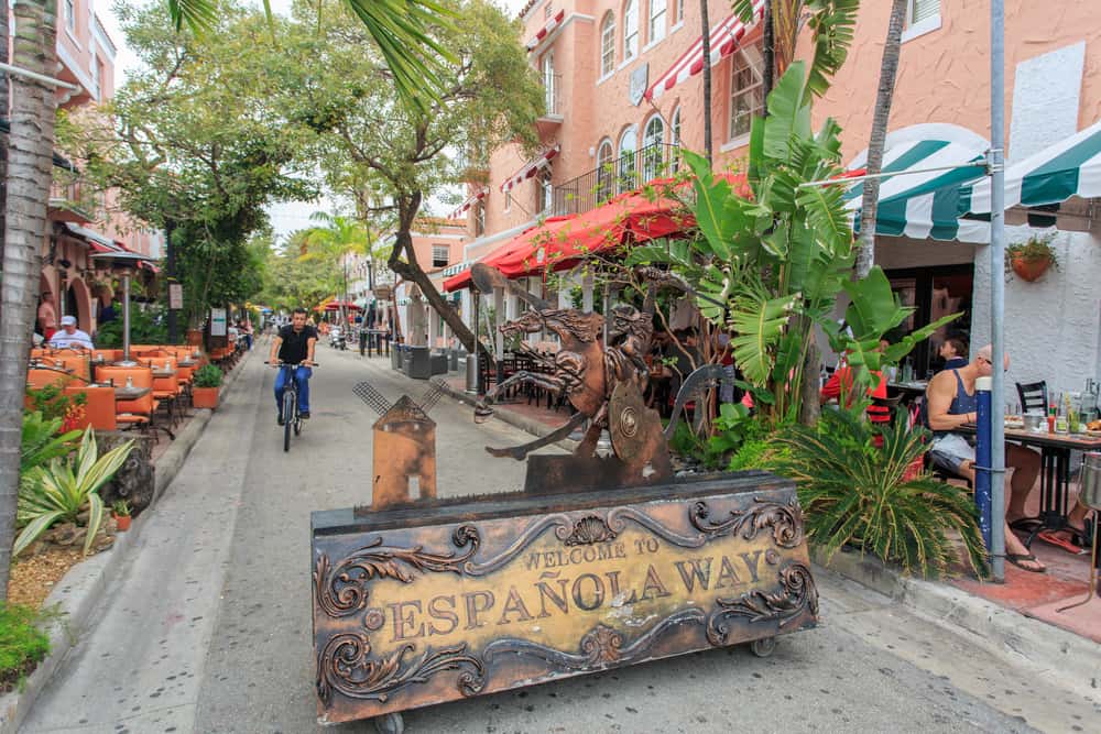 Entrance to Espanola Way with restaurants on either side and an ornate sign that reads "Welcome to Espanola Way.