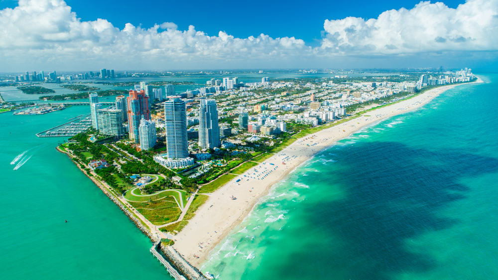 Aerial view of Miami showcasing the long stretch of white sand beaches and beautiful, blue water.