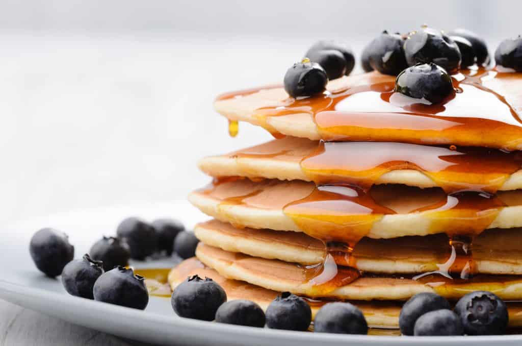 Plate of pancakes with blueberries and syrup.