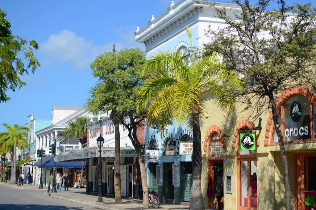 Palm tree lined Duval Street with many brightly colored bars and restaurants.