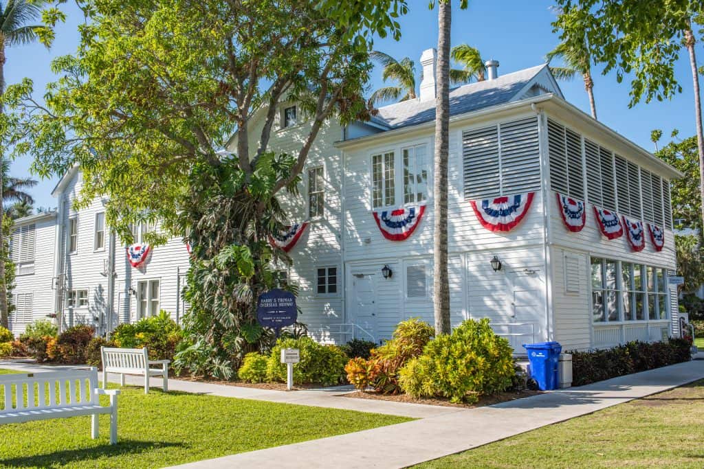 Exterior of Harry S. Truman's Little White House with trees, benches, and bushes.