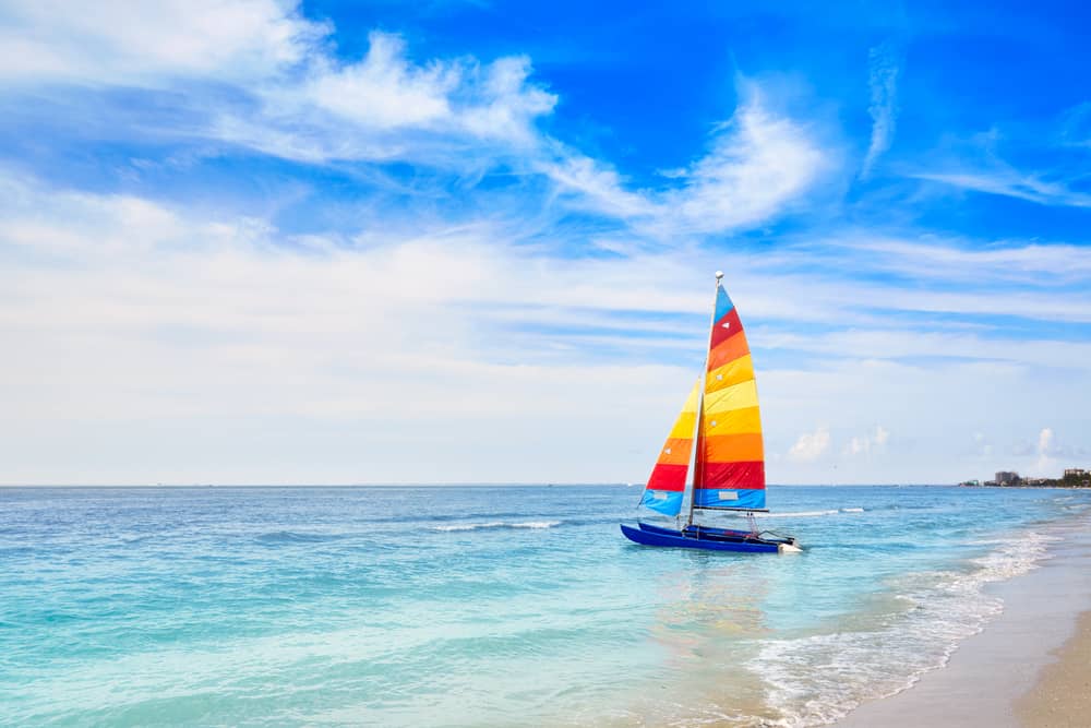 Colorful sails on a catamaran heading out on beautiful blue waters, a scene typical of weekend getaways in Florida.