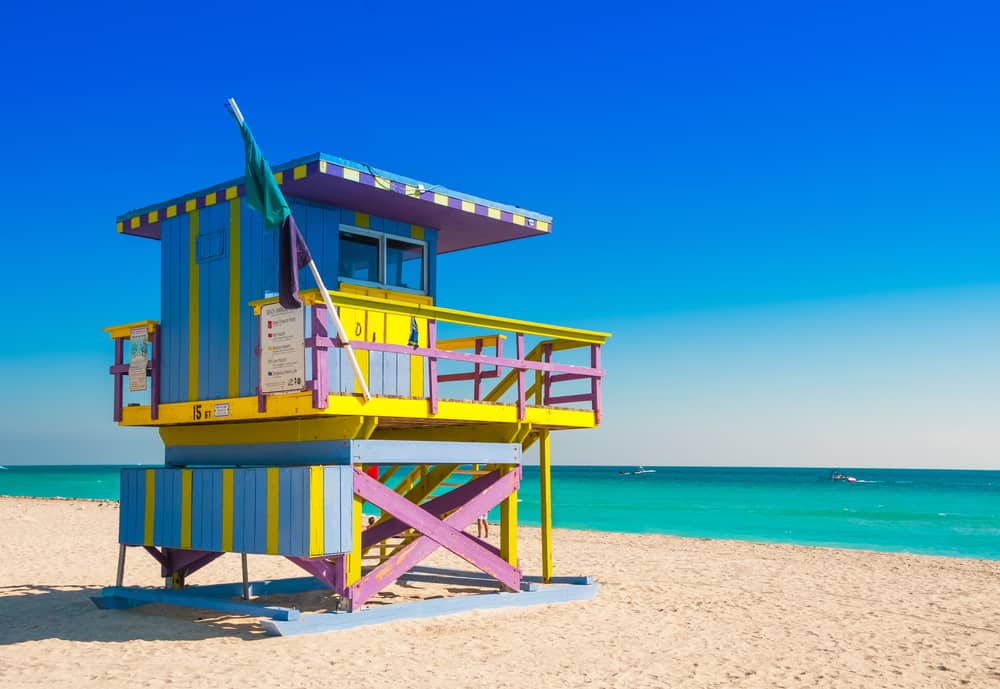 A blue, yellow, and purple lifeguard booth on the sands of Miami Beach, a popular place for weekend getaways in Florida.