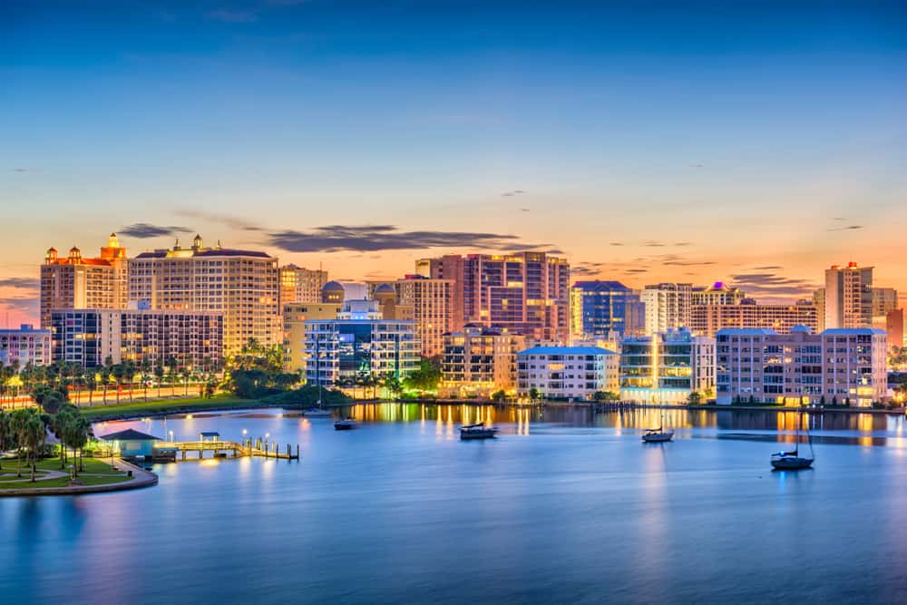 Lit up buildings and sailboats sitting in the bay make up the skyline of Sarasota, a place for weekend getaways in Florida.