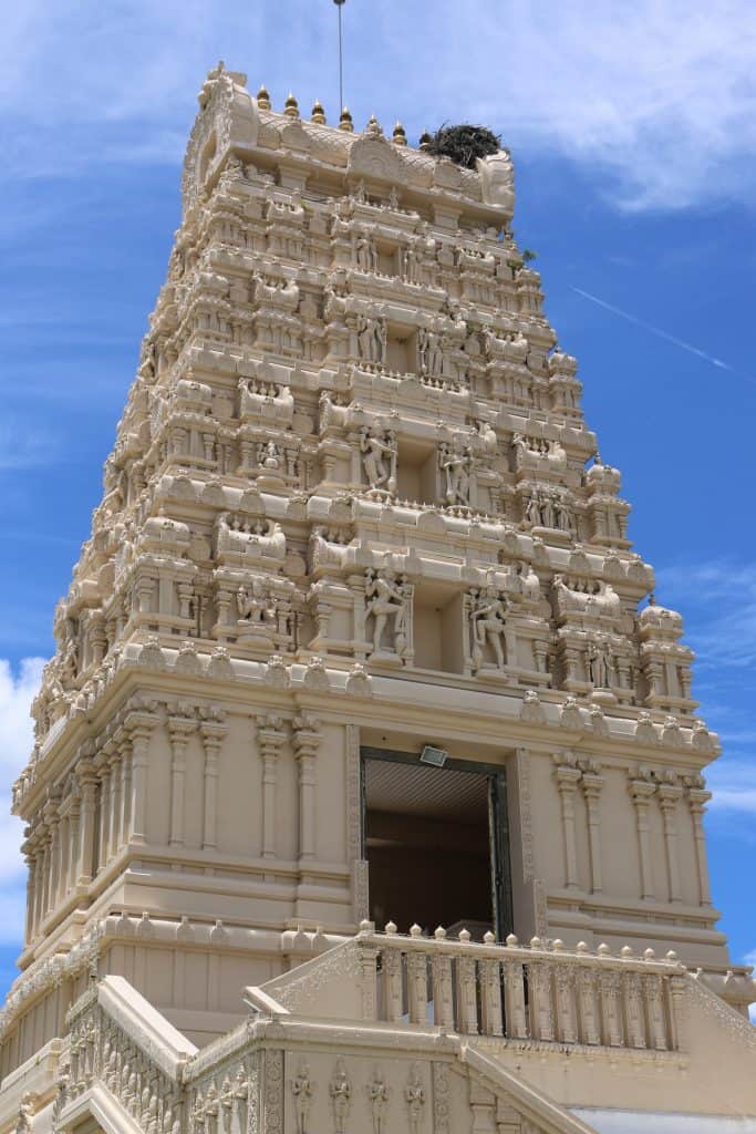 The towering Hindu Temple of Florida. There are intricate carvings and the sky is really blue behind it. 