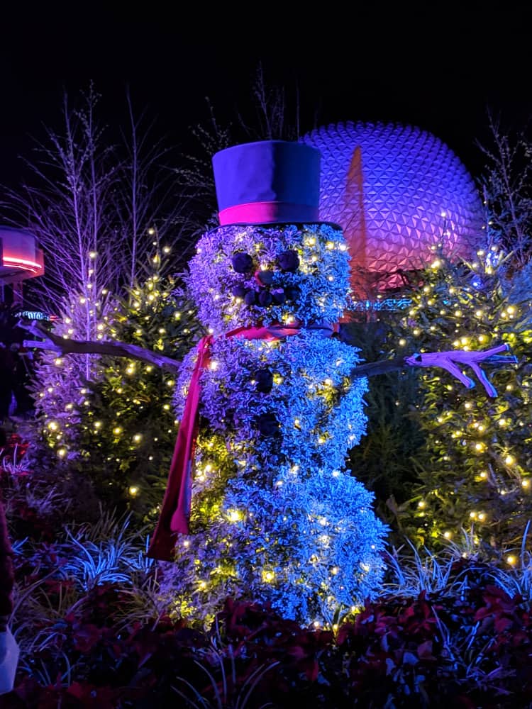 A smiling snowman lights up and greets guests at Disney World during Christmas in Orlando.