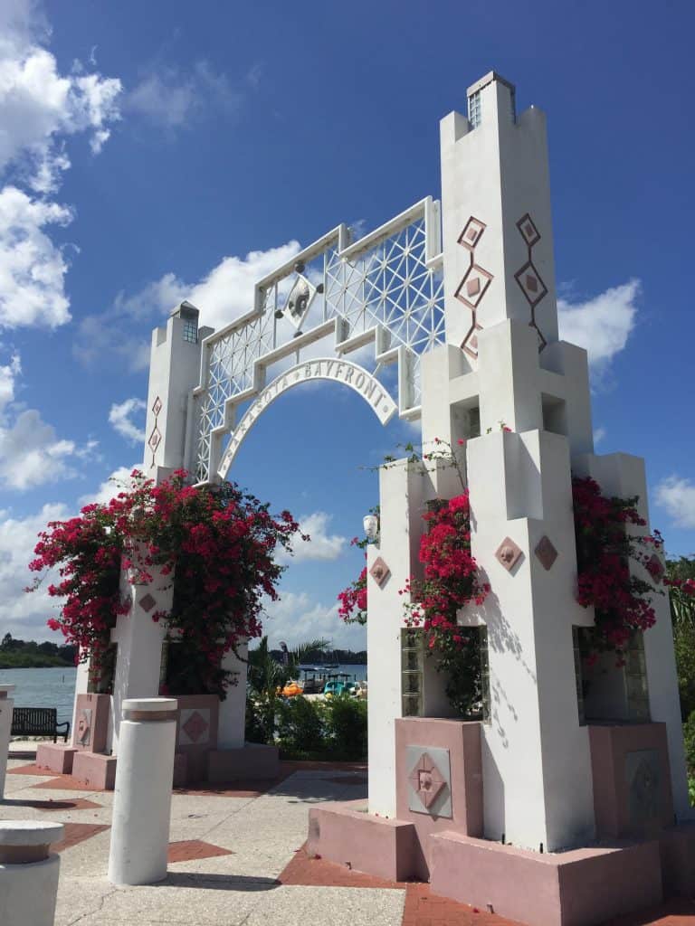 The stone arch entrance to Bayfront Park, with bougainvillea flowers pouring out, visiting which is one of the best things to do in Sarasota.