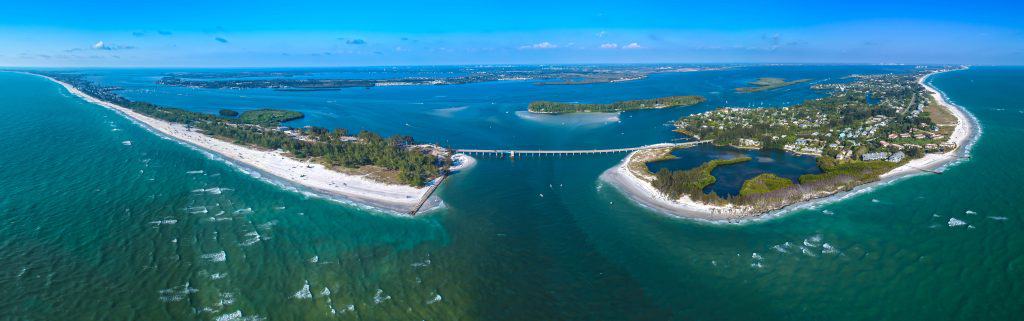 An aerial view of the bridge leading into Sarasota, surrounded by turquoise blue water.