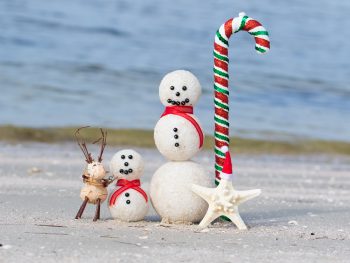 Snowmen made of sand sit on a beach in Florida in winter.