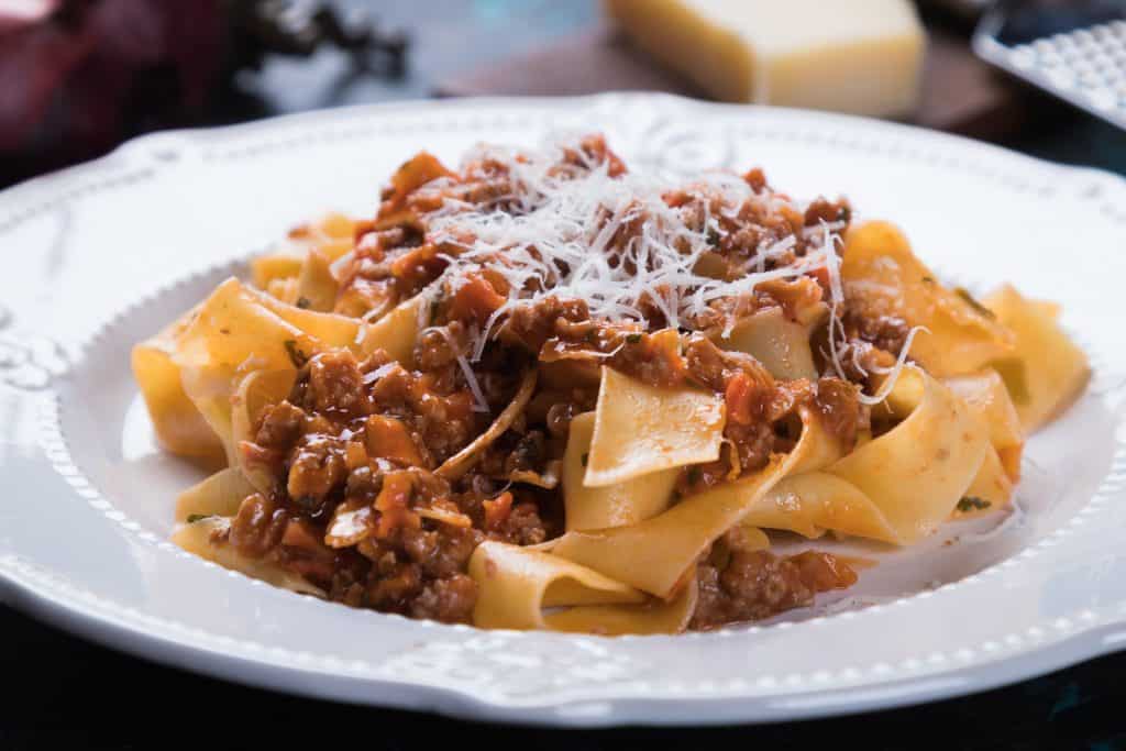 Photo of a white plate serving pasta with a Bolognese sauce. 