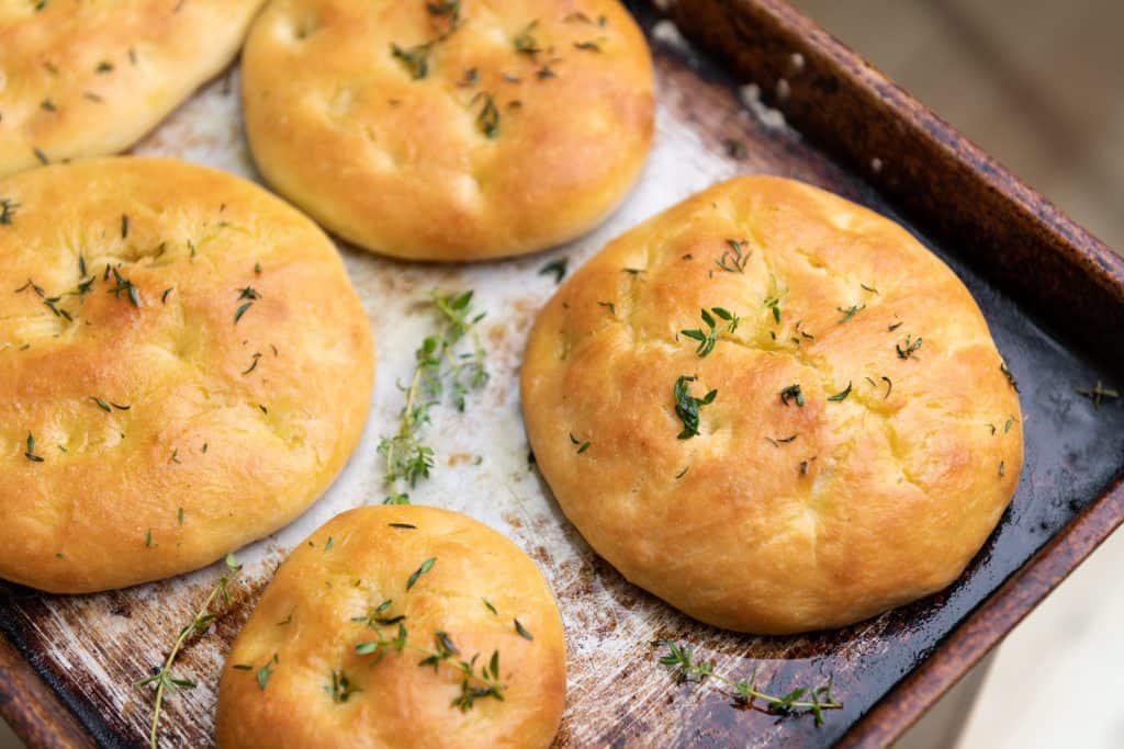 Photo of focaccia bread on a baking pan. 