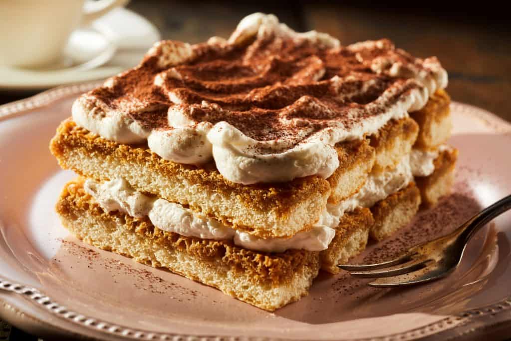 Photo of tiramisu being served on a white plate. 