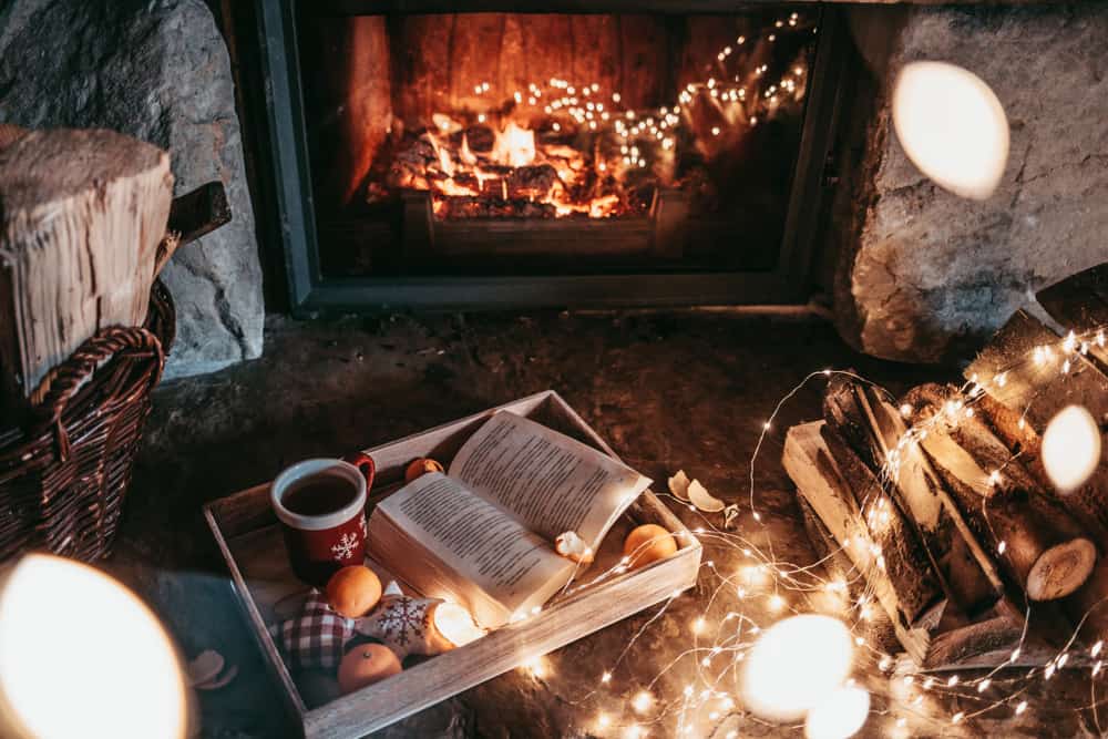 Photo of cozy inside of a cabin with lights and a fireplace. 